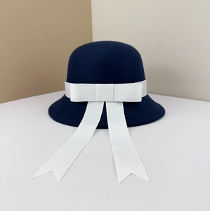 Detail of navy wool felt cloche hat featuring a large white ribbon bow and long streamers