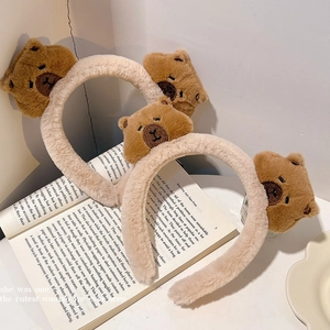 Cute plush capybara headband for hair styling with soft animal ear details on open book