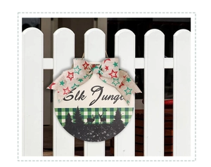 Detail of wooden Christmas sign featuring elk silhouettes and rustic linen bow decoration