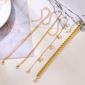 Set di quattro bracciali dorati con ciondolo a farfalla, catena cubana e maglia a spiga
