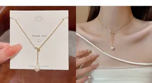 Detailed view of a gold pearl necklace with irregular pendant and stylish thank you card