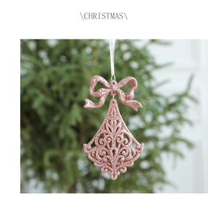 Close-up of pink glitter Christmas bell ornament with a bow on a festive tree