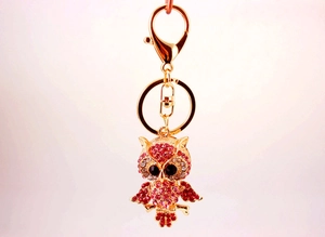 Macro view of golden owl keychain with pink and white rhinestones and black crystal eyes