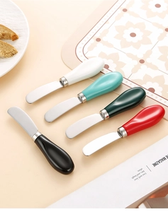 Primo piano di cinque coltelli da burro in acciaio inox con manici in ceramica colorati