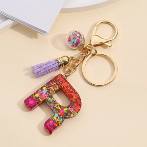 Detail of resin letter R keychain with red purple gradient sequins and purple tassel