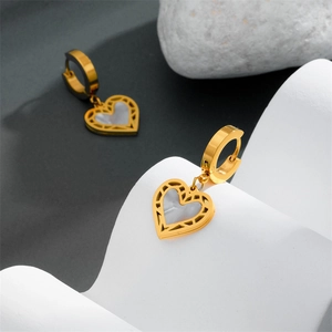 Detailed shot of golden heart earrings with white mother-of-pearl inlay on stone
