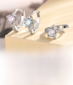 Detail of star-shaped silver hoop earrings featuring pink, blue, and white zircon stones