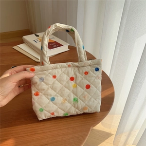 Detailed macro view of quilted cotton mini tote bag featuring vibrant colorful polka dots