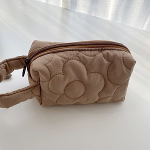 Macro detail of brown quilted floral makeup bag with textured flower pattern and zipper