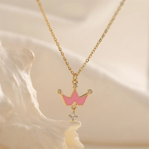 Detail of a gold crown pendant with pink enamel and sparkling gems on a necklace