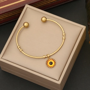 Dettaglio del bracciale rigido dorato con ciondolo occhio greco in scatola beige