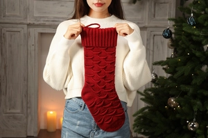 Close-up of deep red knitted Christmas stocking with textured fish scale pattern and hanging loop