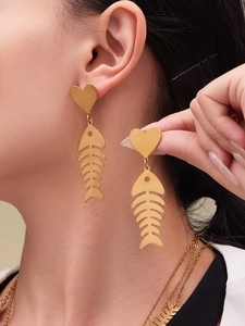 Detail of gold-plated fishbone earrings with heart stud showing professional wear and finish