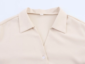 Close-up detail of beige linen shirt collar with V-neck and white round button