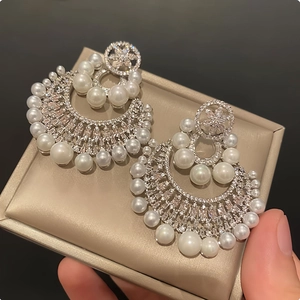 Macro detail of elegant silver-tone flower earrings with pearls and micro-pave crystals