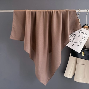 Detail of a brown cotton linen square scarf hanging gracefully on a metal hanger