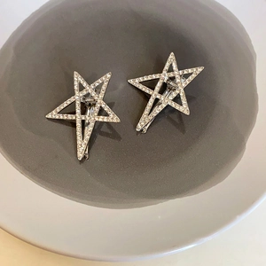 Nahaufnahme glitzernder silberner Stern-Haarspangen mit Strass auf einem Keramikteller