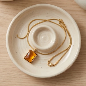 Detailed shot of amber square crystal pendant on 18K gold plated snake chain necklace