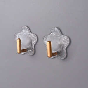 Detail von zwei klebenden sternförmigen Haken mit Goldmetallteilen an grauer Wand