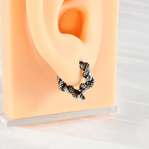 Detail of vintage silver snake earring with scale texture shown on a silicone ear model