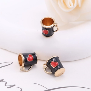 Macro shot of black coffee cup charms with red hearts and golden alloy trim for DIY jewelry