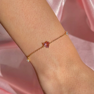 Detailed macro view of a pink heart gemstone bracelet on elegant pink silk fabric
