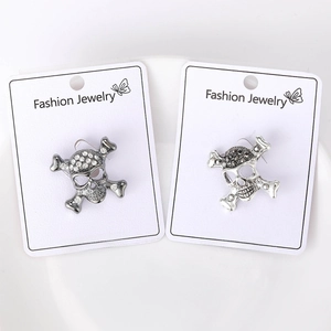 Detailed macro view of crystal skull and crossbones brooches in silver and gunmetal finishes