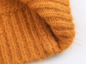 Détail macro du tricot jaune gingembre montrant une texture douce et duveteuse