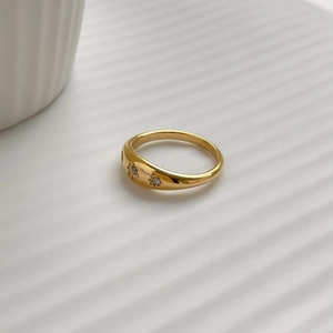 Close-up of gold star ring with micro-set zircons on a white textured background