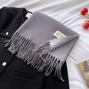 Close-up of grey cashmere-style scarf featuring twisted fringes and brand textile label