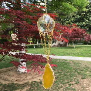 Detail of K9 crystal ball with gold metal mesh and yellow agate slice hanging ornament