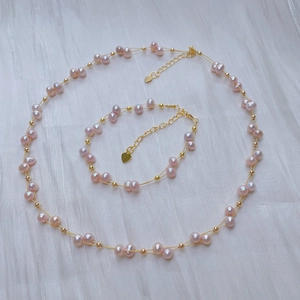 Detail of pink pearl necklace and bracelet with gold wire and heart pendant on white gauze