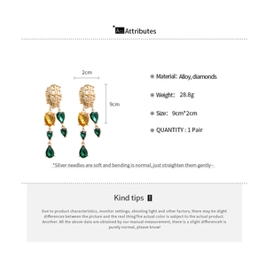 Detailed spec sheet showing gold geometric drop earrings with yellow and green crystals