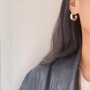 Close-up of polished 925 sterling silver chunky hoop earrings and minimalist ear cuff