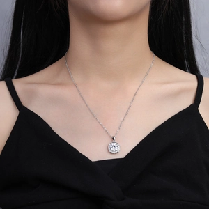 Close-up of a square silver pendant necklace with clear crystals worn by a model