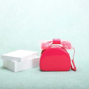 Detailed view of pink patent leather telephone-shaped handbag with handset handle detail