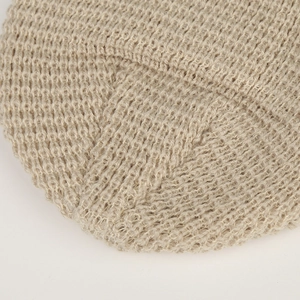 Dettaglio ravvicinato del berretto in maglia beige con trama a uncinetto e finitura