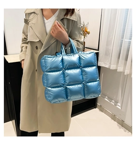 Dettaglio della borsa tote trapuntata blu metallizzata lucida tenuta da una modella