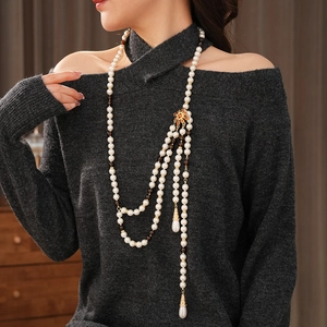 Detail of layered vintage pearl necklace with golden flower clasp and teardrop pendants