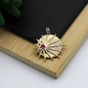 Macro detail of starburst gold pendant with a red center stone and micro-pave crystals