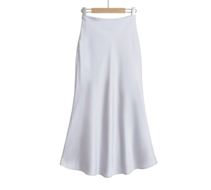 Détail d'une jupe longue blanche en satin à taille haute avec une texture fluide