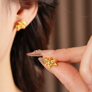 Detail of matte gold pony earrings shown as close-up on ear for a retro luxury look