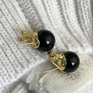 Macro shot of 925 silver black onyx hoop earrings on a cream knit background