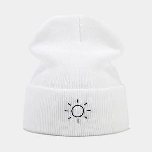 Close-up of sun embroidery detail on white cuffed knit beanie with soft texture