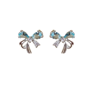 Silver bow knot earrings with blue teardrop stones and zircon crystals on white background