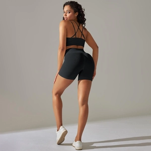 Detail der überkreuzten Rückengurte des schwarzen Sport-BHs und der Yoga-Shorts im Fitness-Set