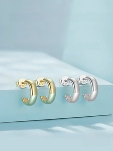 Detail of C-shaped S925 sterling silver hoop earrings in gold green and polished silver