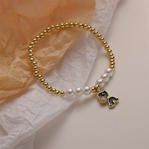 Close-up of beaded bracelet with pearls, gold beads, and a black enamel cat pendant