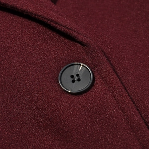 Detailed macro view of high-quality dark four-hole button on burgundy wool coat fabric