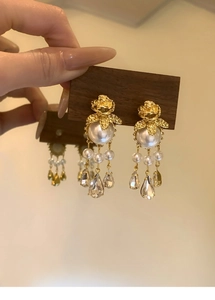Détail de boucles d'oreilles rose dorée vintage avec perles blanches et gouttes de cristal